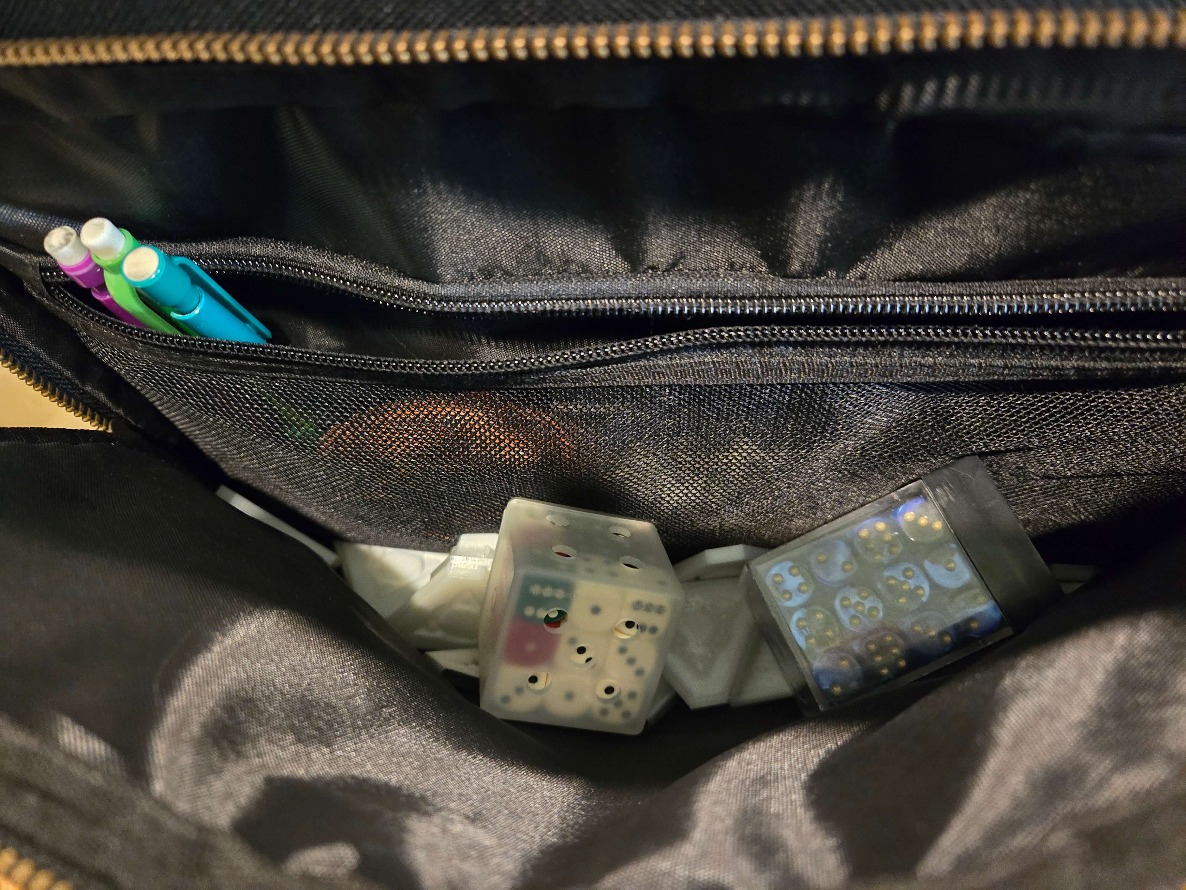 Several pencils, dice, etc stored in the front pouch